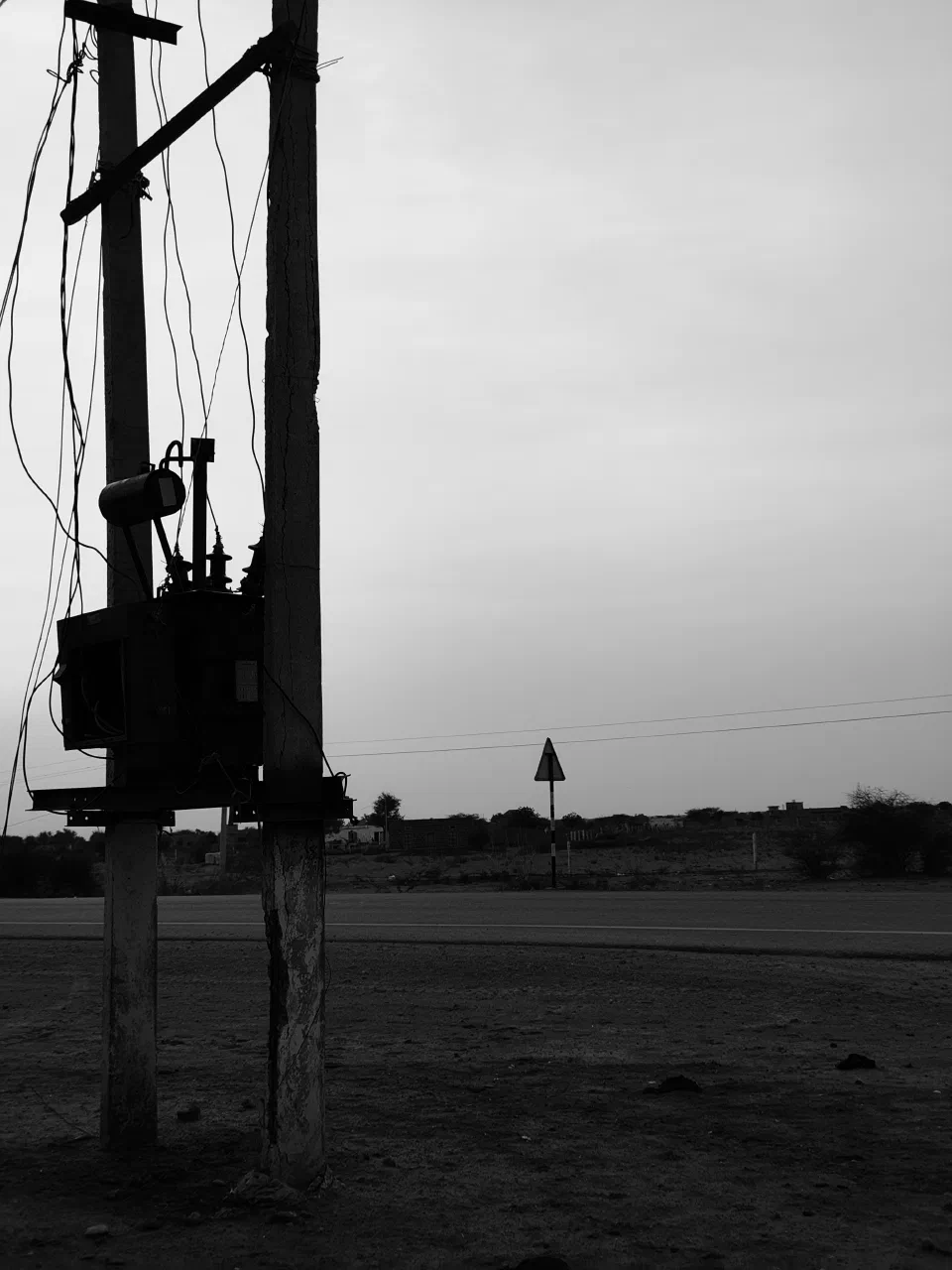 A tall structure beside open land in black and white