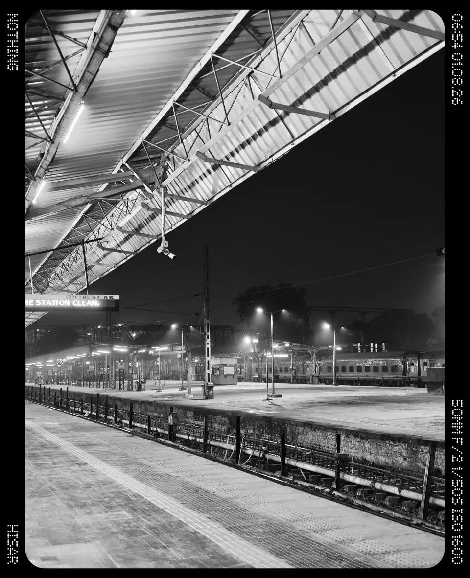 Railway platforms beneath a station roof in black and white